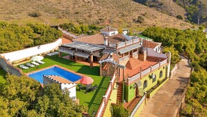Una villa grande con piscina, varios balcones y un jardín exuberante.
