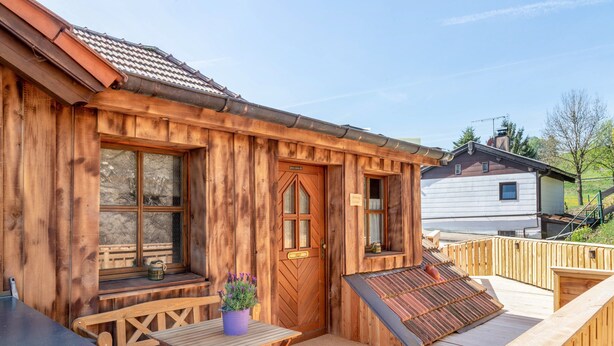 A wooden cabin with a deck, a door, and a window. - Apartment 'Fewo Edelweiss' with Private Sun Terrace and Wi-Fi (Breitenberg)