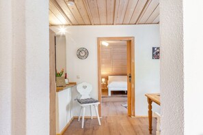 Un couloir menant à une chambre dotée d’un plafond en bois, d’une horloge, d’une petite table et d’une chaise.