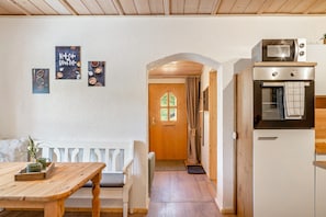 Una cocina acogedora con un banco de madera, un refrigerador blanco y un microondas.