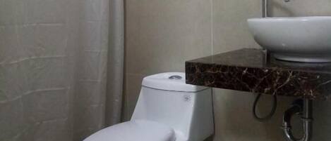 A bathroom with a toilet, a sink, and a trash bin.