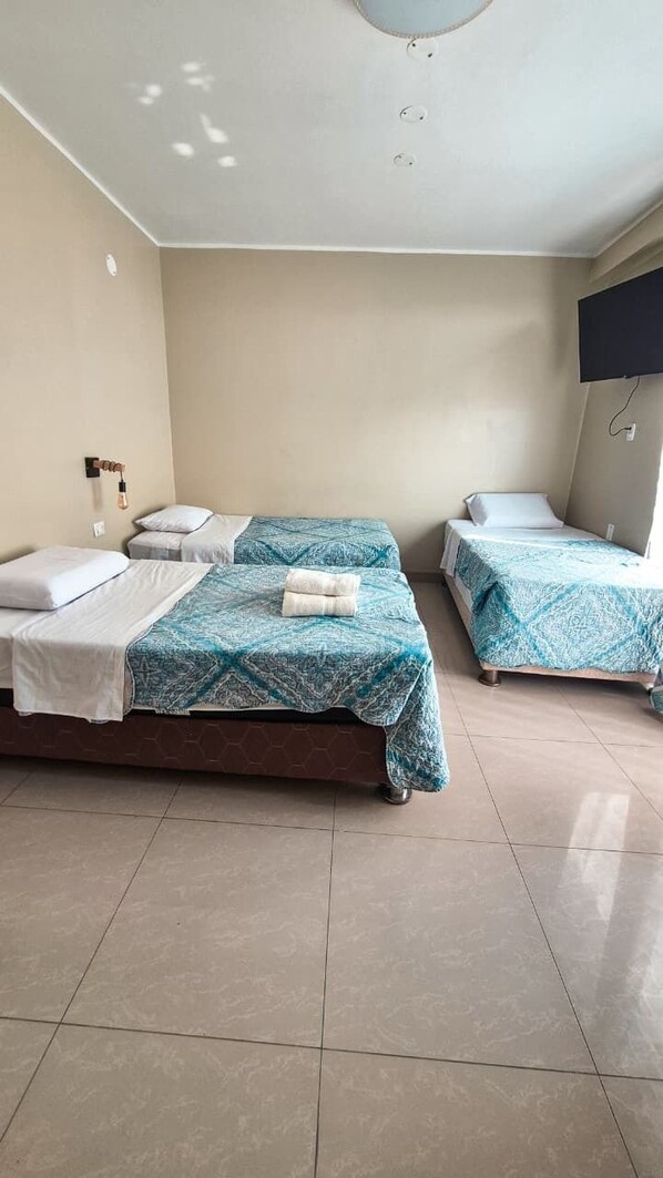 A room with two beds, a flat-screen TV, and a ceiling light fixture. - Willy's House (Paracas)