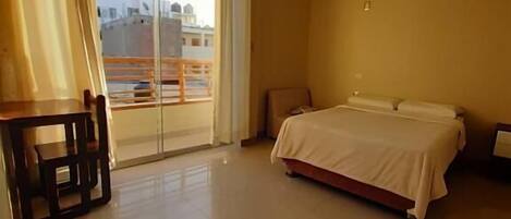 A hotel room with a bed, a desk, and a chair.