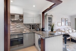A modern kitchen with stainless steel appliances, a built-in washing machine, and a granite countertop.