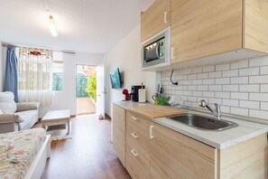 Eine moderne Küche mit Holzschränken, einer eingebauten Mikrowelle, einem Spülbecken und einem Fenster mit Blick auf einen Garten.
