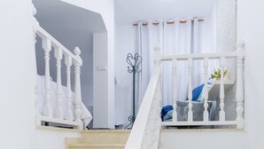 Un escalier avec des balustrades blanches menant à un palier où se trouve un lit.