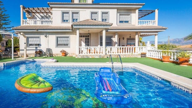 Une maison à deux étages avec une piscine, un patio couvert et une pelouse bien entretenue.