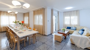 Un salon moderne comprenant un canapé, une table basse et un coin repas avec des chaises et une table mise pour le repas.
