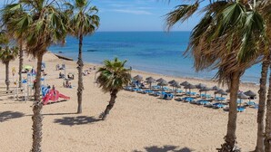 A beach with palm trees, a playground, and beach umbrellas. - Feel at Home by Fidalsa (Torrevieja)