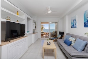 A modern living room with a flat-screen TV, a sofa, a coffee table, and a view of the ocean. - Feel at Home by Fidalsa (Torrevieja)