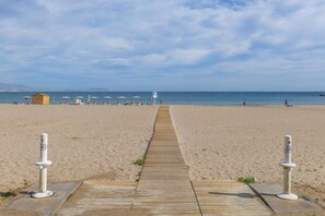 A beach with a wooden walkway leading to the sea, umbrellas, and a lifeguard tower. - Fidalsa Bella Vista Junto al mar (El Campello)