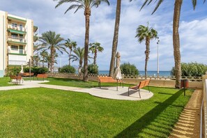 Ein Innenhof mit Palmen, Bänken und Blick auf das Meer.