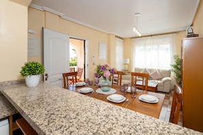 A well-lit, modern kitchen with granite countertops, a dining area with a wooden table set for four, and a cozy living room with a sofa and a lamp. - Honey Life Villa by Fidalsa (Orihuela)