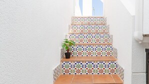A narrow stairway with colorful patterned tiles and a potted plant on the first step. - Fidalsa Summer Breeze (Orihuela)