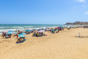 A crowded beach with numerous colorful umbrellas and people relaxing on the sand.