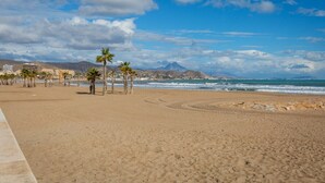 A beach with palm trees, a clear sky, and mountains in the distance.