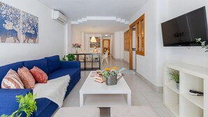 Ein modernes Wohnzimmer mit einem blauen Sofa, einem weißen Couchtisch und einem Flachbildfernseher.