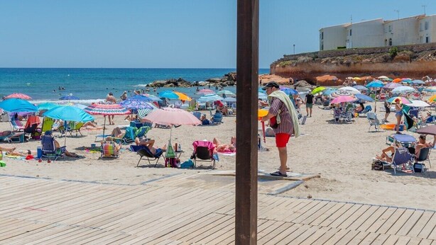 Een strand met een houten terras en parasols.