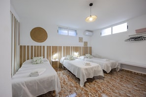 Ein Hotelzimmer mit zwei Betten, einem runden gewebten Wandbild, einer Deckenleuchte und einem Fenster.