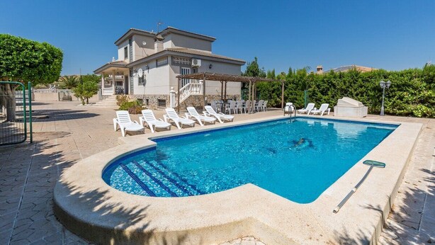A swimming pool with lounge chairs, a pergola, and a building in the background. - Fidalsa Grand White House (Mutxamel)