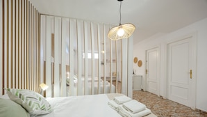 A hotel room with a bed, a nightstand, a lamp, a mirror, and a door. - Fidalsa Grand White House (Mutxamel)