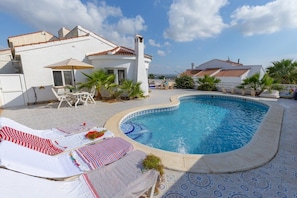 A swimming pool with lounge chairs and umbrellas, surrounded by a white building with a tiled roof. - Fidalsa Golf & Beach (Rojales)