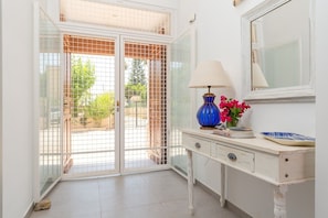 A room with a white desk, a lamp, a mirror, and a view through a glass door. - Harmony Villa by Fidalsa (Daya Vieja)