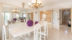 A spacious dining area with a large white table, white chairs, and a chandelier. - Fidalsa Mediterranean Beachfront (Orihuela)