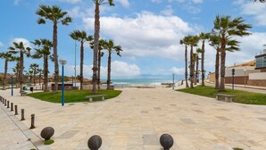 A paved promenade with palm trees, benches, and bollards, leading to a beach. - Fidalsa Mediterranean Beachfront (Orihuela)