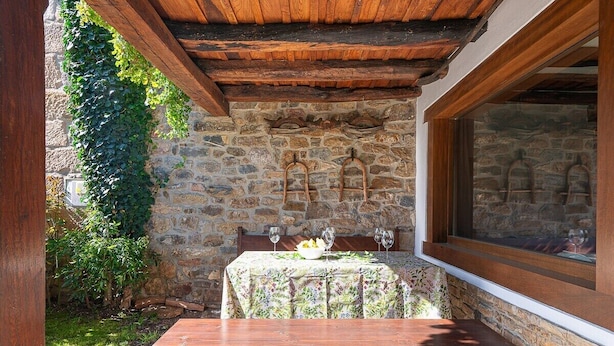 Un muro de piedra con un banco de madera y una mesa con mantel floreado.