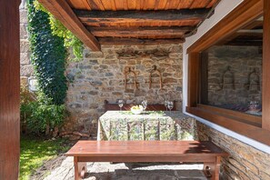 A stone wall with a wooden bench and a table with a floral tablecloth. - Fidalsa House of Views (Cabezon de Liebana)