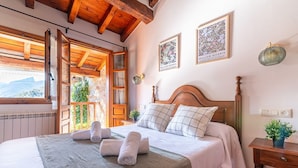 Un dormitorio con una cama de madera, un ventanal y una lámpara fijada a la pared.