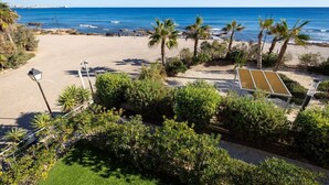 A beach view with palm trees, a sandy area, and a clear blue sky. - Fidalsa Paradise Sea Punta Prima (Torrevieja)