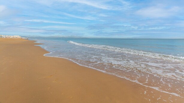 A beach with a wide sandy shore and gentle waves, under a clear sky. - Beach Haven by Fidalsa (Guardamar del Segura)