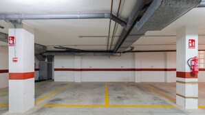 A parking garage with white walls, red and yellow parking lines, and fire extinguishers. - Beach Haven by Fidalsa (Guardamar del Segura)