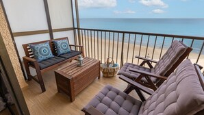 A balcony with a wooden sofa, two cushioned chairs, a small wooden table, and a wicker basket. - Beach Haven by Fidalsa (Guardamar del Segura)