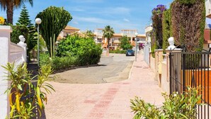 A residential street with houses, a paved road, and greenery. - Goldencore by Fidalsa (Orihuela)