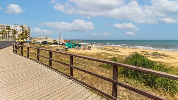 A wooden boardwalk leading to a beach with a lifeguard station and beachgoers. - Fidalsa Coastal Soul (Torrevieja)