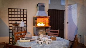 An outdoor patio with a brick oven, wooden chairs, a table set with tea set, and a decorative fence. - Fidalsa Coastal Soul (Torrevieja)
