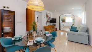 A modern dining area with a glass table, blue chairs, and a wicker pendant light. - Fidalsa Coastal Soul (Torrevieja)