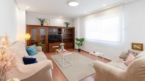 Una sala de estar con un sofá, una mesa de centro, un televisor y una estantería.
