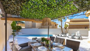 An outdoor dining area with a pool in the background, covered by a leafy pergola. - The Big Chill by Fidalsa (Rojales)