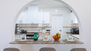 A modern kitchen with white cabinets, a granite countertop, and a central island with seating. - The Big Chill by Fidalsa (Rojales)
