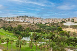 A coastal town with a golf course, palm trees, and buildings in the background. - The Big Chill by Fidalsa (Rojales)