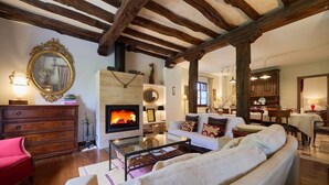 A cozy living room with a fireplace, wooden beams, a sofa, and a dining area. - The Basque Experience by Fidalsa (Otxandio)