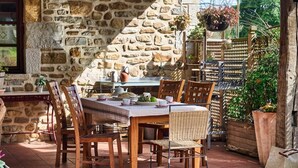 A stone wall, a wooden table with chairs, and hanging planters. - The Basque Experience by Fidalsa (Otxandio)