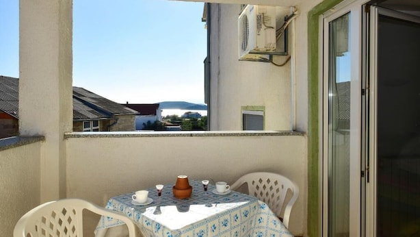 Ein Balkon mit Tisch für zwei Personen, Blick auf Gebäude und einer Schiebeglastür.