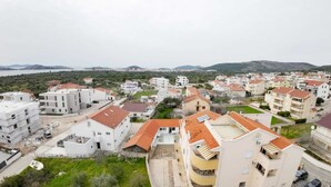 Ein Wohngebiet mit Mehrfamilienhäusern, einige mit Balkonen, und einer hügeligen Landschaft im Hintergrund.