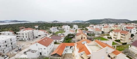 A residential area with apartment buildings, some with balconies, and a hilly landscape in the background.