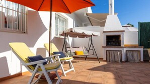 A patio with two yellow lounge chairs, a swing chair, and a brick oven. - Happiness Corner by Fidalsa (Pilar de la Horadada)